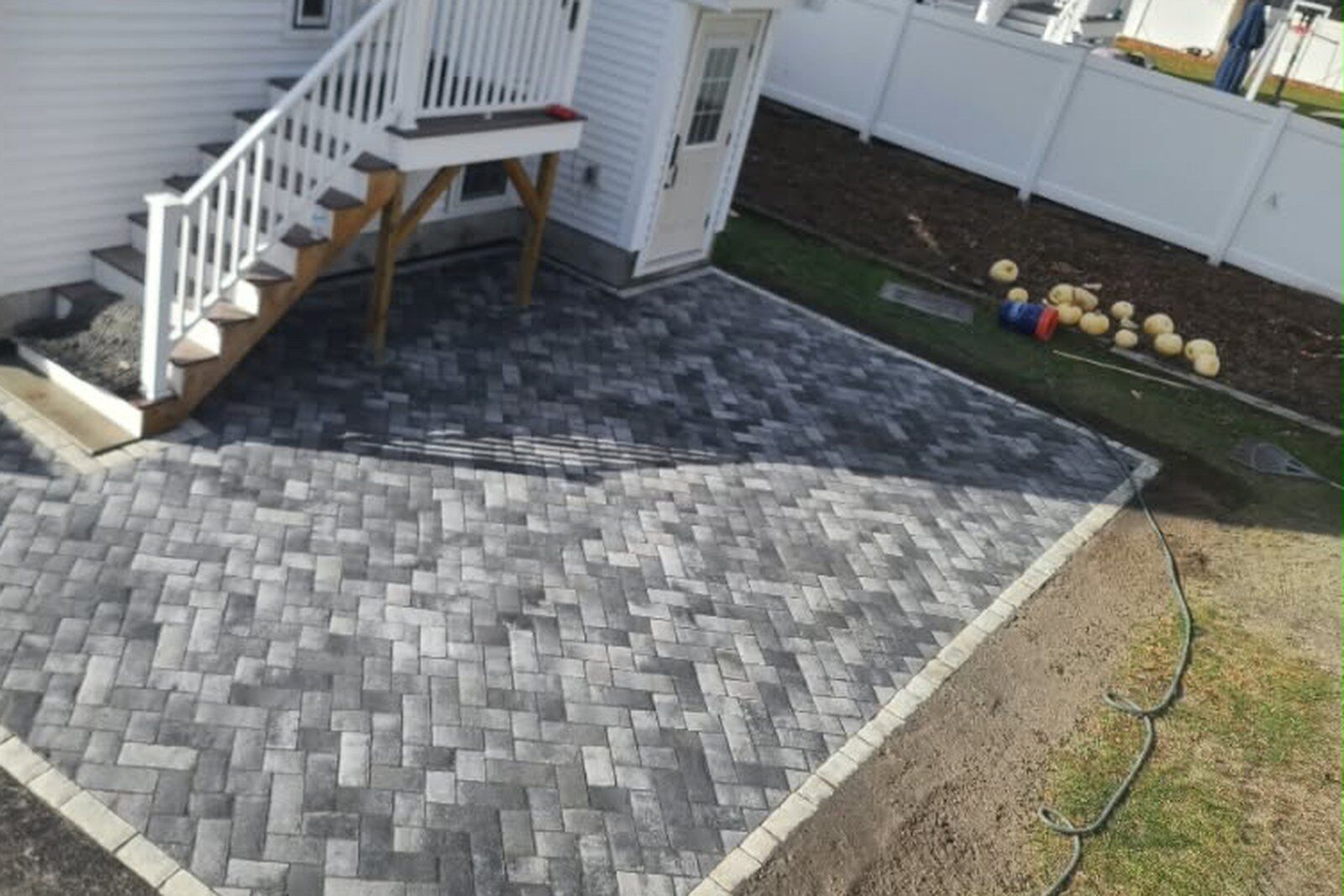 A herringbone stone patio laid off the back stairs of a house.