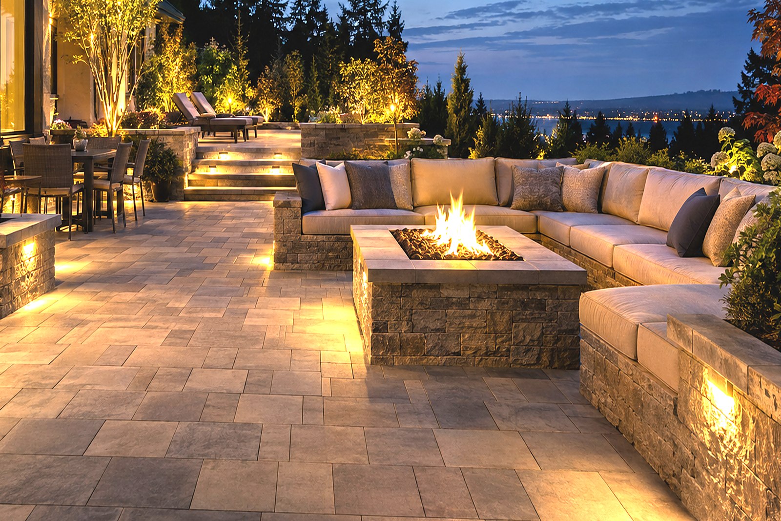 A circular stone fire pit set into a stone patio with seating around it.